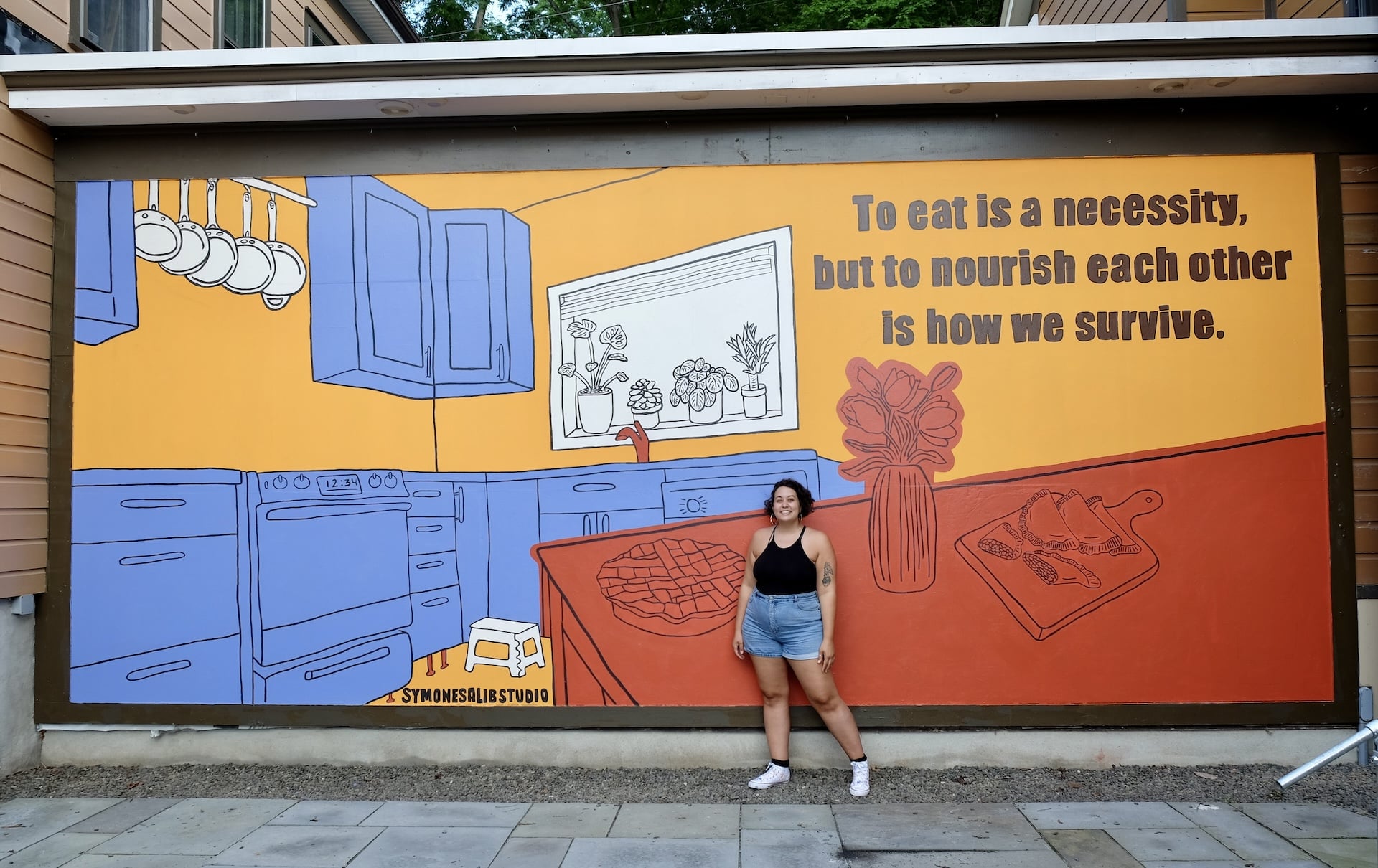 Artist Symone Salib stands in front of her mural.