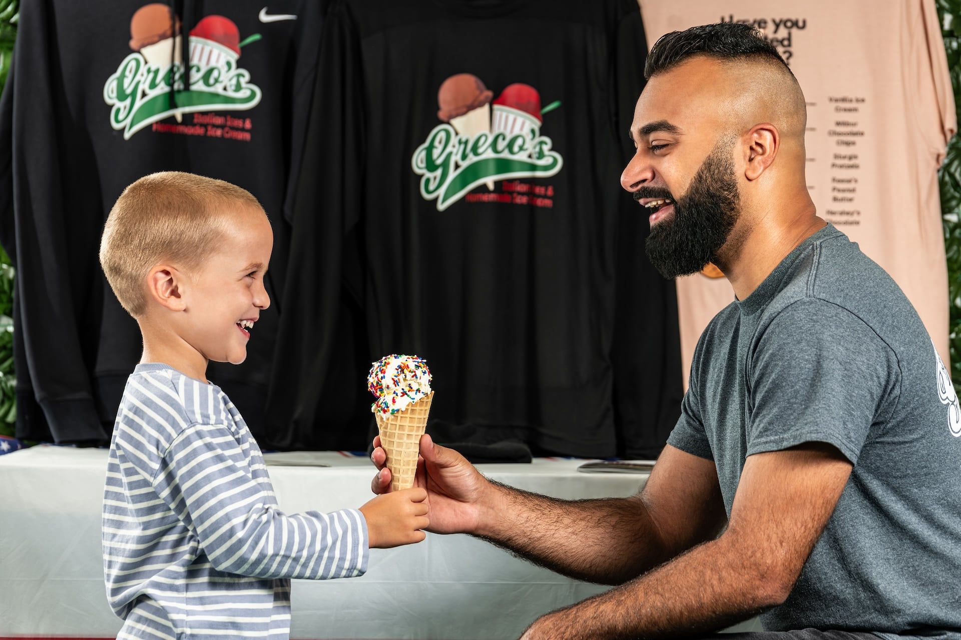 Hamzah Dawood of Greco's Italian Ice and Homemade Ice Cream giving a customer a cone.