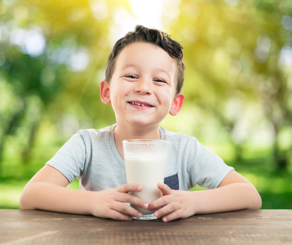 Fill A Glass With Hope; a young boy smiles at the camera with a glass of milk