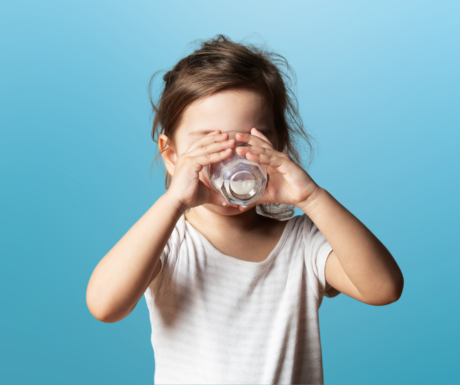 Little girl drinks milk from a glass.