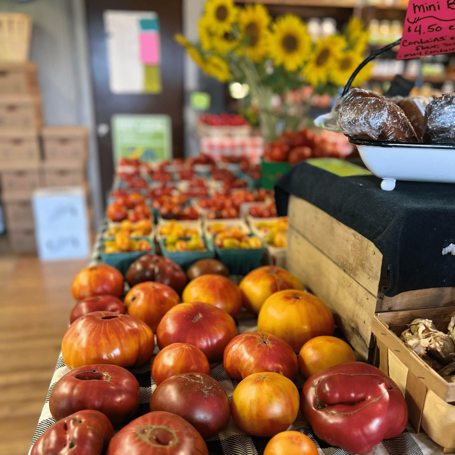 JP's Farmers Market table with tomatoes and sunflowers.