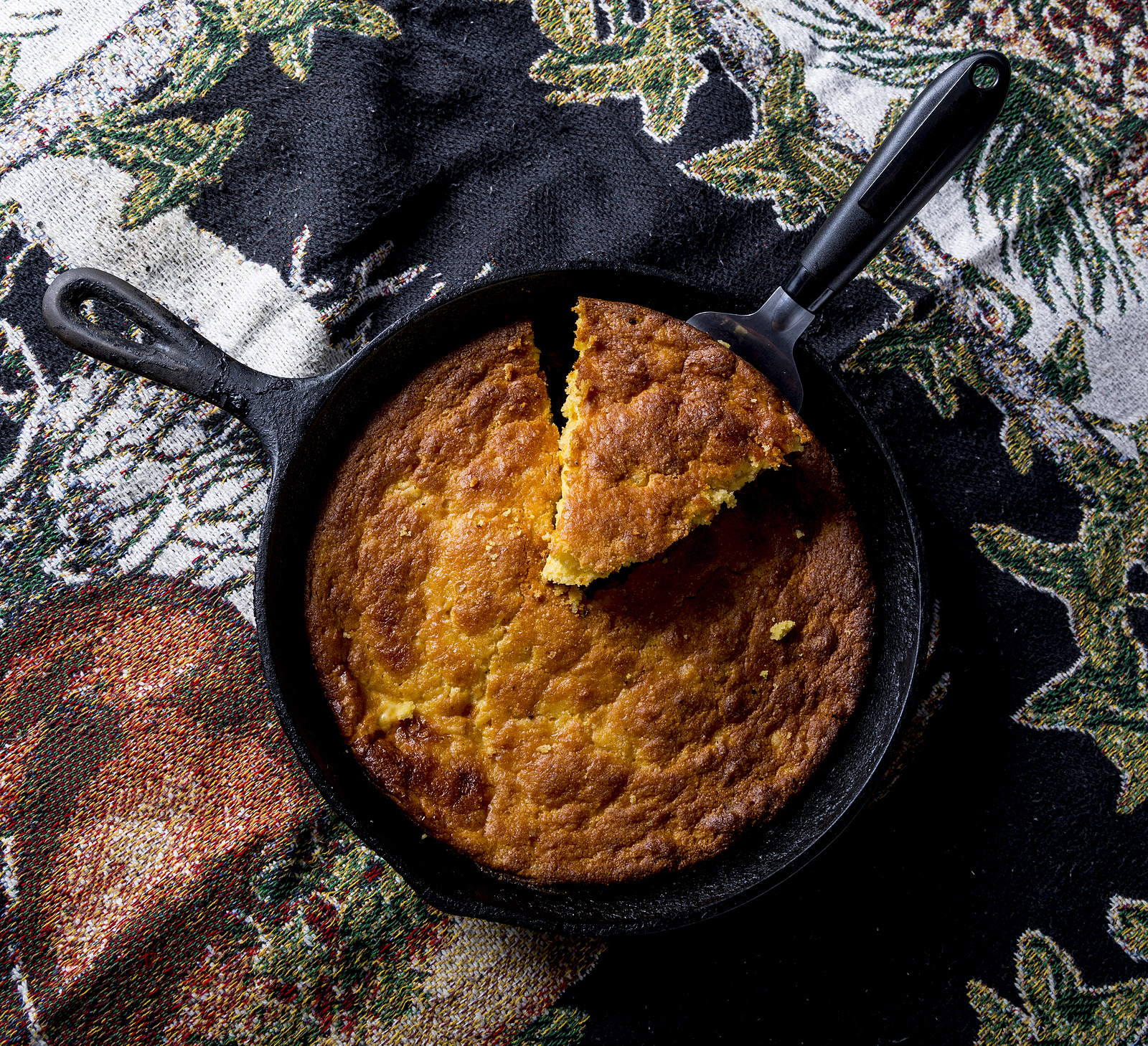 Home Style corn bread being served from a cast-iron skillet.