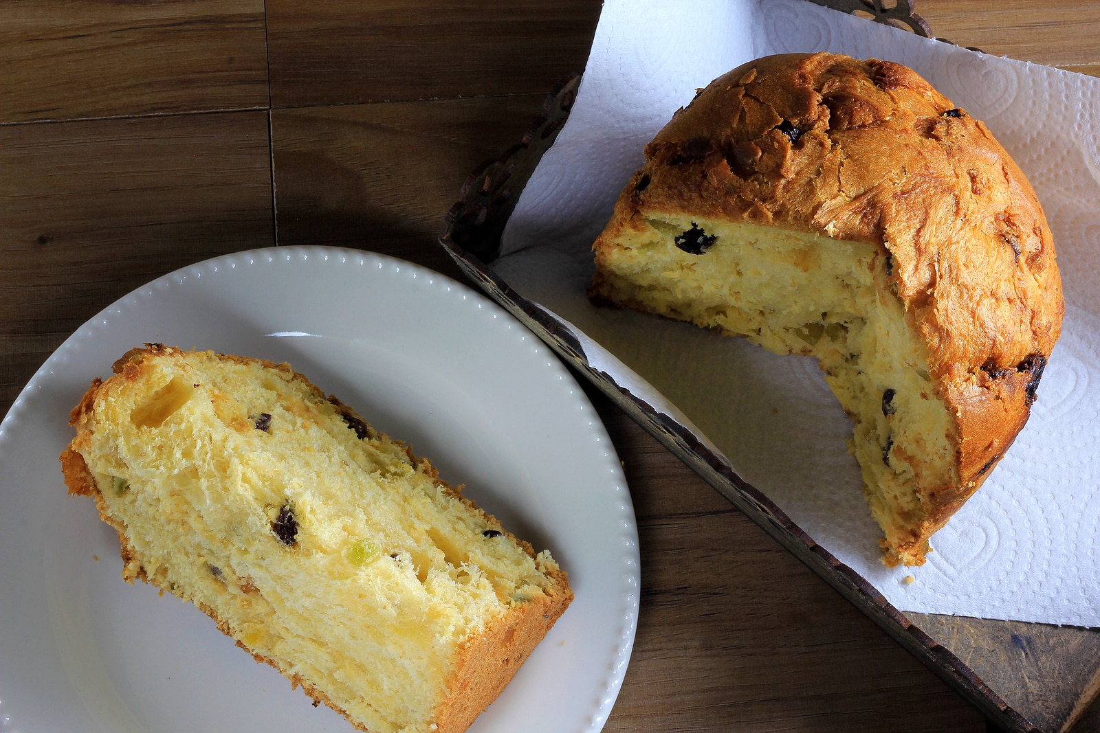 Panettone inside box on wooden table, slice of panettone on plate, top view