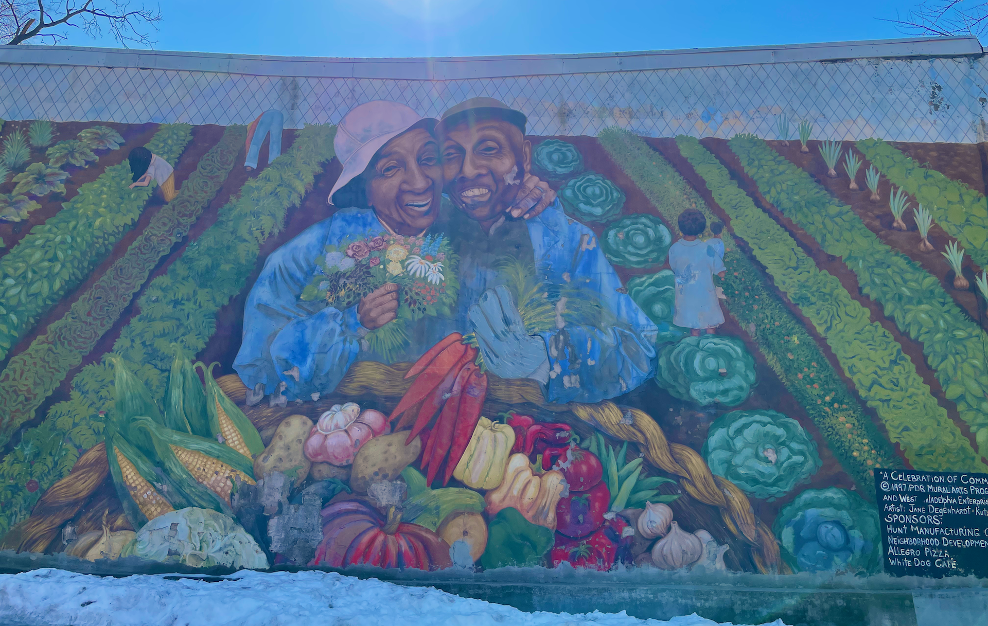A mural in West Philadelphia with a loving couple holding fresh produce from their garden.