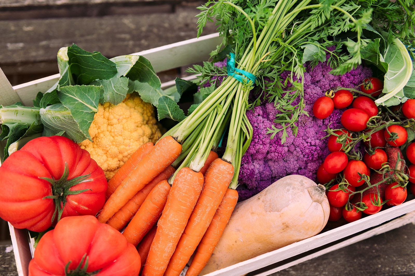 close up of a box full of vegetables and greens in a crop field, healthy eating and ecological farming concept